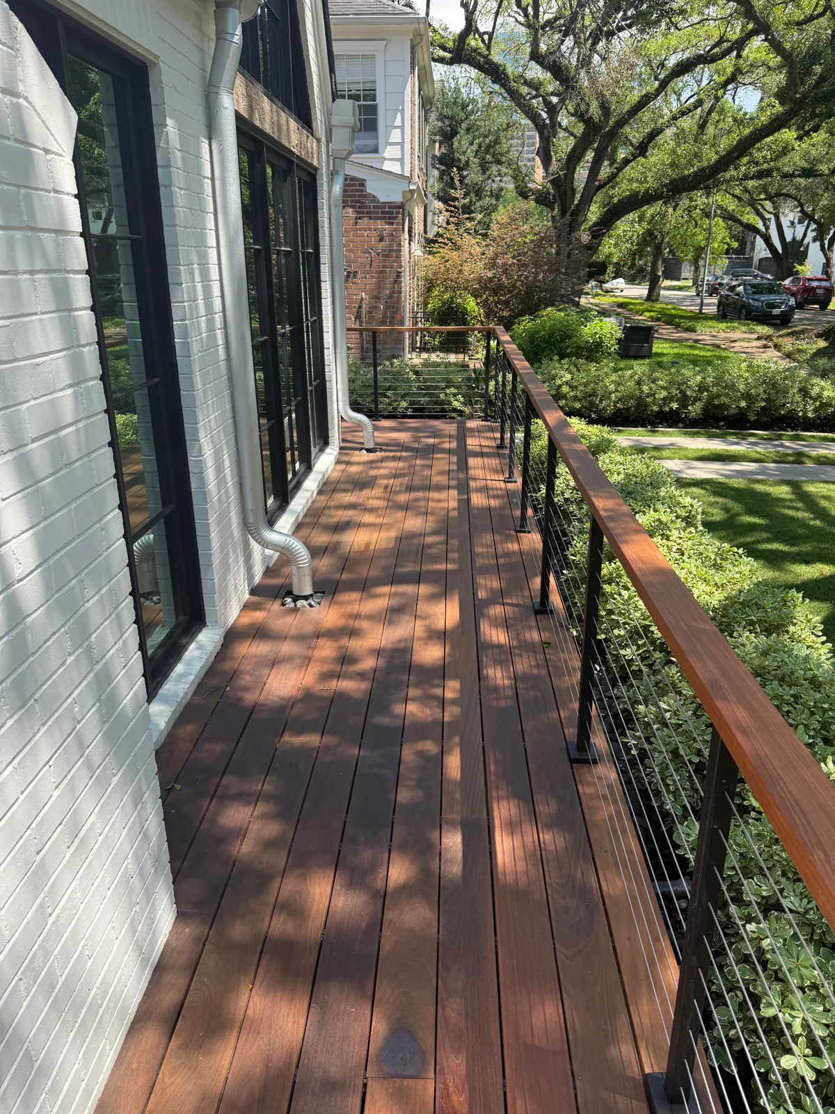 Raised front deck with railing beside a house and mature tree